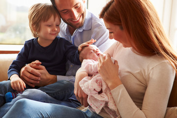 family sitting on sofa with newborn baby