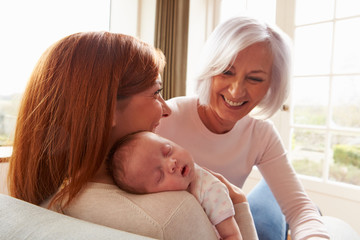mother and grandmother with sleeping newborn baby daughter