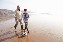 Grandfather And Grandson Playing Football On Winter Beach