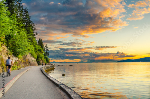 Fotografía Sunset over The Seawall of Vancouver with cyclist in motion