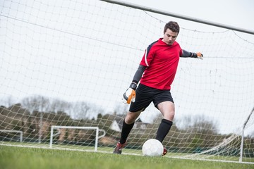 Poster - Goalkeeper in red kicking ball away from goal