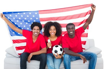 Wall Mural - Happy football fans in red sitting on couch with usa flag