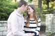 © EugeneF - Happy young caucasian couple sitting at the park both hugging and smiling.