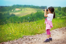 Little Girl Looking Through Binoculars Outdoor. She Is Lost