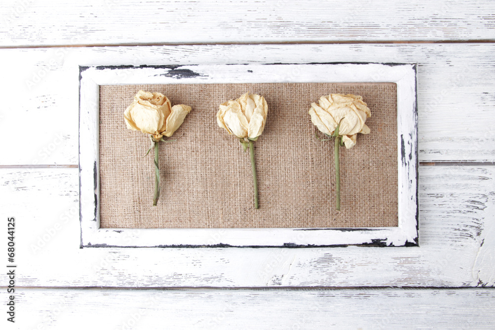 Wooden frame with dried flowers on wooden background