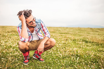 Poster - laughing crouched man passing his hand through his hair