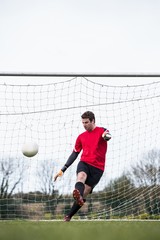 Poster - Goalkeeper in red kicking ball away from goal