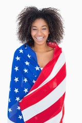 Wall Mural - Pretty girl wrapped in american flag smiling at camera