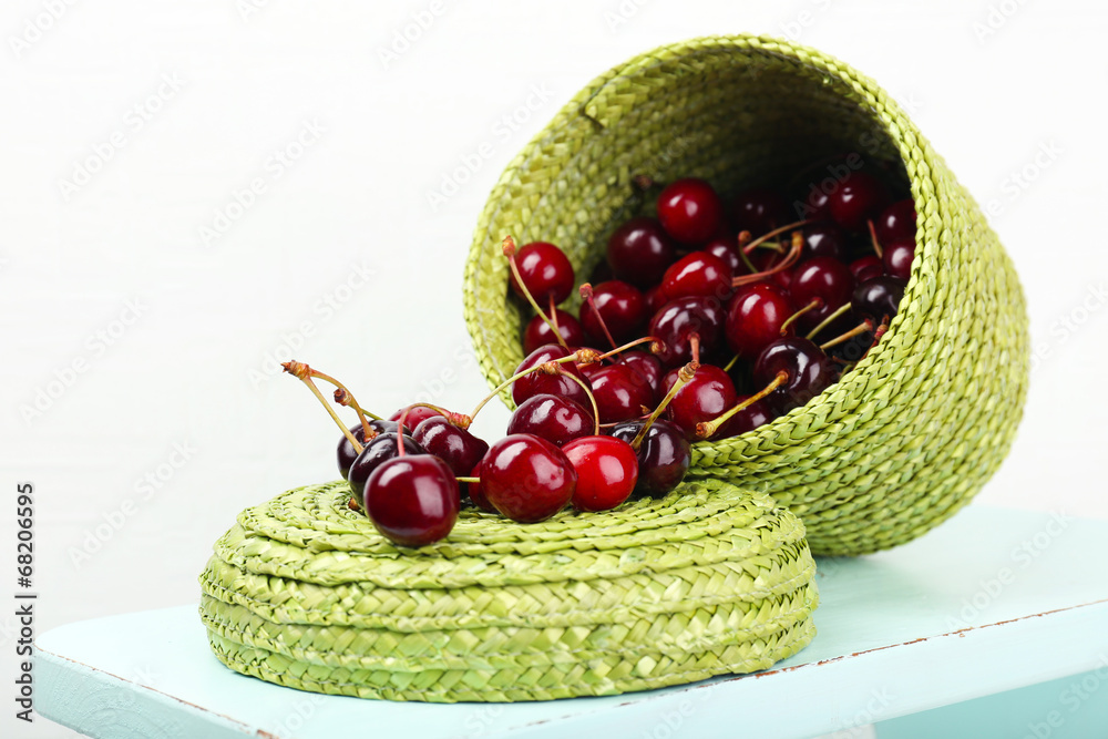 Fresh cherries in basket on white wall background