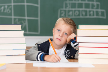 Canvas Print - grundschüler sitzt müde zwischen schulbüchern