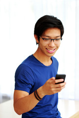 Canvas Print - Happy asian man using smartphone at home