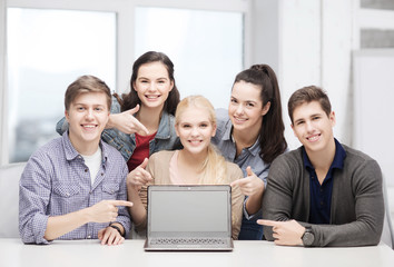 Wall Mural - smiling students pointing to blank lapotop screen