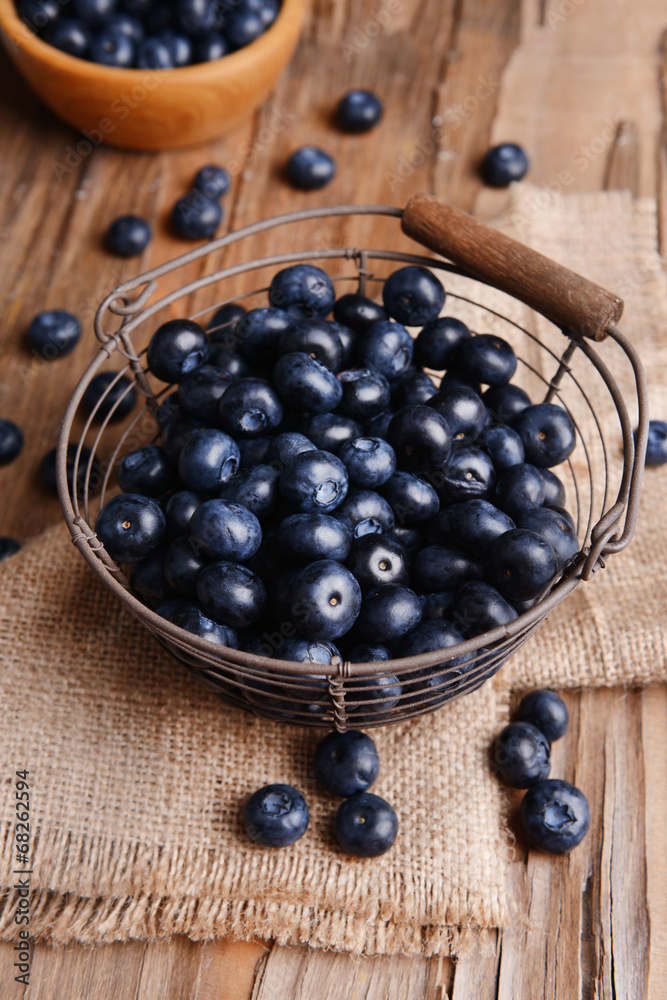Delicious blueberries in wicker basket on table close-up