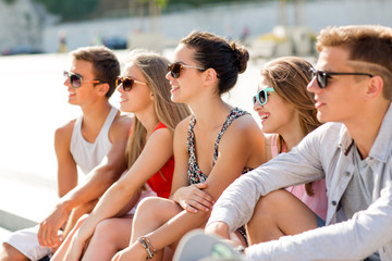 Wall Mural - group of smiling friends sitting on city square