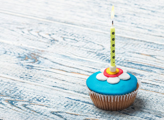 Cupcake with floral decorations and a burning candle