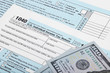 © niyazz - USA 1040 Tax Form with two 100 US dollar bills over it