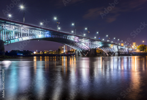 Fototapeta na wymiar Backlit bridge at night and reflected in the water.