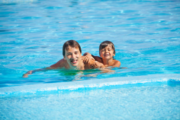 Wall Mural - Smiling man with boy in swimming pool