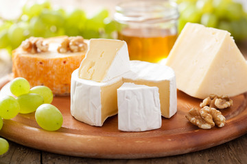 Wall Mural - cheese plate with camembert, cheddar, grapes and honey