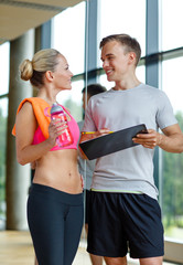 Wall Mural - smiling young woman with personal trainer in gym