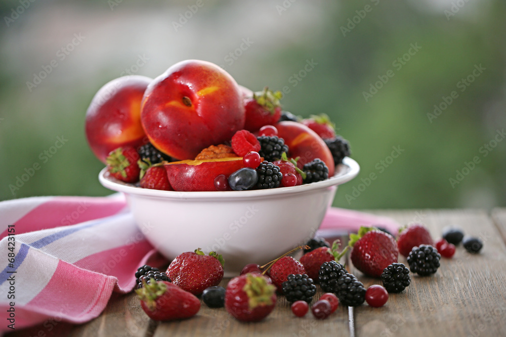 Peaches and berries in bowl on table close-up
