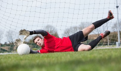 Wall Mural - Goalkeeper in red saving a goal during a game