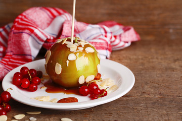 Sticker - Sweet caramel apple on stick with berries, on wooden table