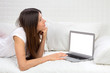 © Dmitry Lobanov - Young successful woman lying on a sofa with laptop paying bills
