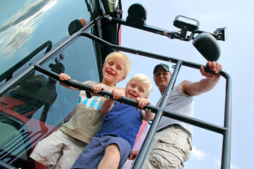 Children and Their Father Smiling as the Climb a Farm Tractor