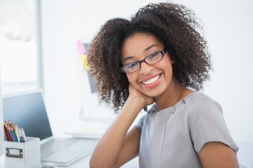 young pretty designer smiling at camera at her desk