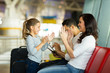 © michaeljung - young mother playing a game with daughter at airport