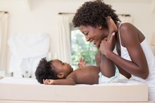 Happy African American Mother With Baby Girl On Changing Table