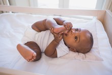 Adorable Baby Boy Lying In His Crib Chewing Foot