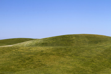 view of bare green hills with a blue sky.