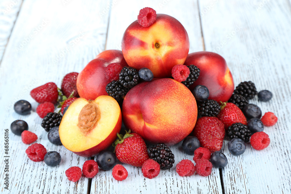 Peaches with berries on wooden table close-up