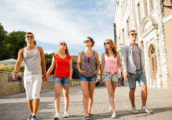 Wall Mural - group of smiling friends walking in city