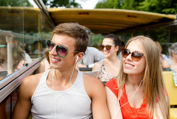 smiling couple with earphones traveling by bus