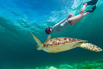 Young woman snorkeling with sea turtle