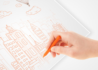 Fototapete - A person drawing sketch of a city with balloons and clouds on a