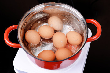 Wall Mural - Eggs in boiling water in pan on electric hob