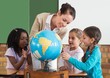 © WavebreakmediaMicro - Cute pupils and teacher in classroom with globe