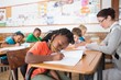 © WavebreakmediaMicro - Cute pupils writing at desk in classroom
