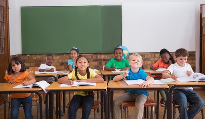Cute pupils smiling at camera in classroom