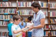 © WavebreakmediaMicro - Cute pupils and teacher reading book in library