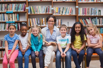 Wall Mural - Cute pupils and teacher reading in library