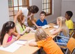 © WavebreakmediaMicro - Pretty teacher standing with pupils at desk