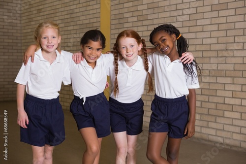 Fotografie, Obraz Cute pupils smiling at camera in PE uniform