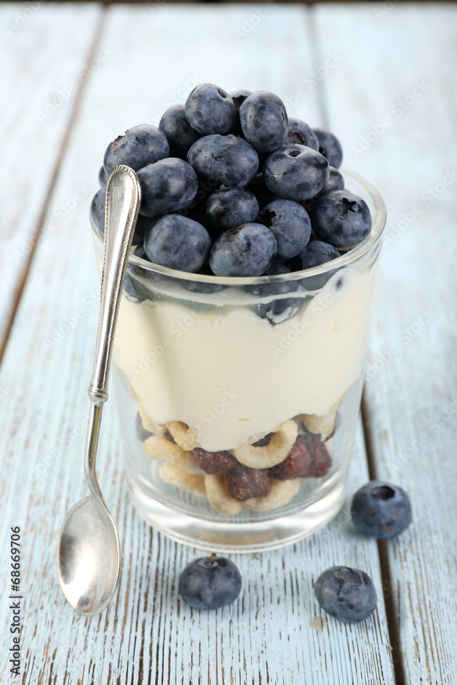 Natural yogurt with fresh blueberries on wooden table