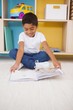 © WavebreakmediaMicro - Cute little boy sitting on floor reading in classroom