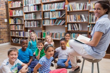 Wall Mural - Cute pupils sitting on floor in library